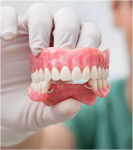 Hand with white glove displaying denture model.